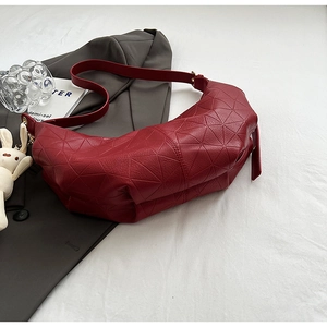 Detail of dark red dumpling bag with geometric texture and cute white bunny charm