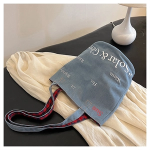 Dettaglio della borsa tote in denim blu con fodera a quadri rossi e stampa bianca