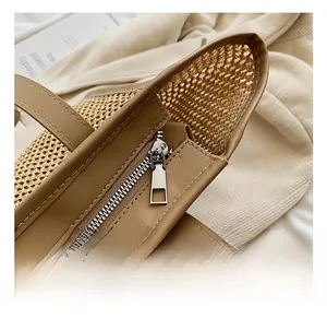 Détail de la fermeture éclair argentée et garniture en cuir brun sur un grand sac en paille