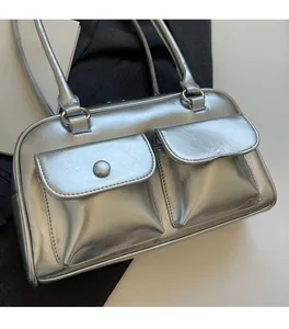 Détail du sac à bandoulière argenté montrant la texture plissée et les poches cargo