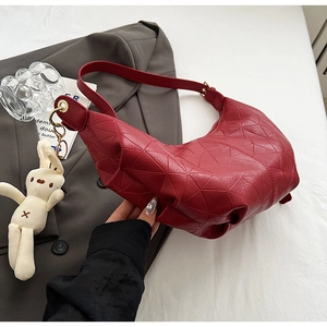 Detail of dark red crescent bag with geometric triangle embossing and a plush rabbit charm