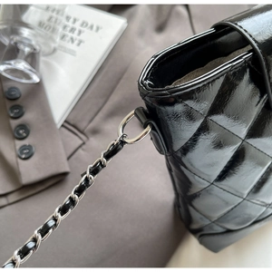Detail of black patent leather bucket bag with quilted pattern and silver chain strap