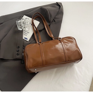 Detailed view of brown glossy Boston bag with premium PU leather and metal feet