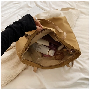 Detailed interior of a spacious light brown nylon tote bag showing zipper and ample storage