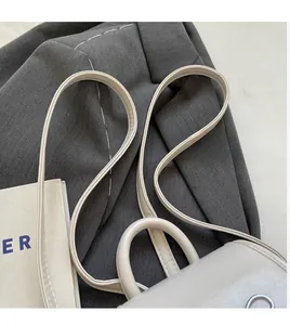 Detail of smooth cream white leather backpack with slim straps on a grey suit background