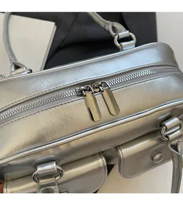 Détail macro des doubles fermetures éclair en métal sur un sac à bandoulière argenté brillant