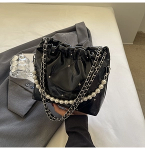Detail of black glossy leather shoulder bag with silver rivets and elegant pearl chain