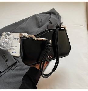 Detail of black glossy leather bag showing Coih 2dn logo and knot strap with silver buckle
