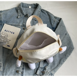 Detail view of white canvas backpack with plush wings and transparent inner pocket
