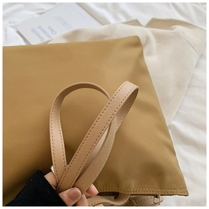 Detail of khaki oxford tote with lychee grain leather strap and golden metal zipper