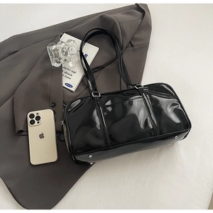 Detail view of glossy black patent leather pillow bag with silver metal bottom studs
