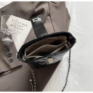 Detail view of the black quilted patent leather bucket bag showing interior compartments