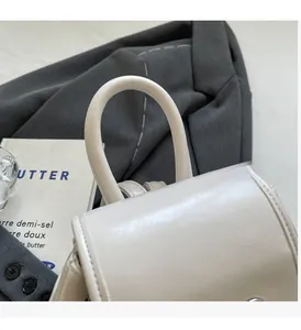 Detail of the soft off-white leather handle and flap of this minimalist handbag
