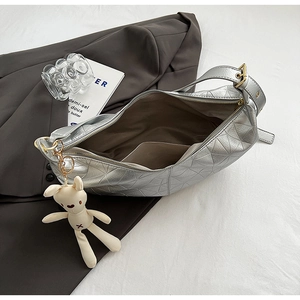 Detail of silver dumpling bag with geometric stitching and white rabbit plush charm