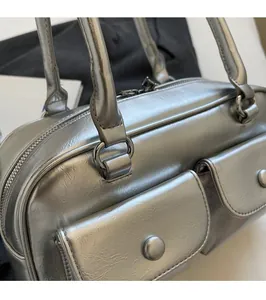 Détail d'un sac à main argenté montrant les poches avant et la texture du métal poli