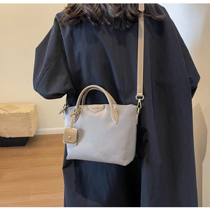 Detail of grey Oxford tote bag featuring faux leather handles and a mini card holder charm