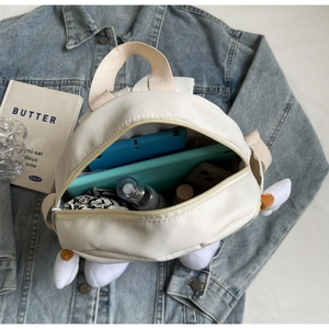 Internal storage detail of white canvas mini backpack with tablet and small gadgets
