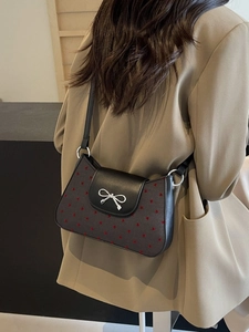 Schicke schwarz-graue Schultertasche mit rotem Herzmuster und silberner Schleife am Blazer