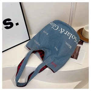Dettaglio borsa in denim azzurro con fodera a quadri e ricamo Sun sul manico