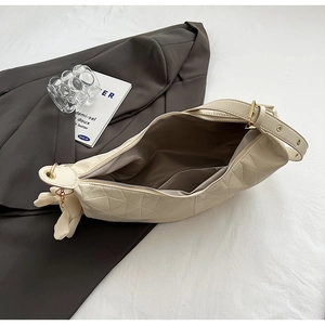 Detail view of cream dumpling bag with triangle quilting and spacious interior compartment
