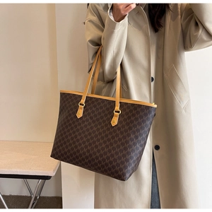 Close-up of vintage monogram pattern on brown tote bag with leather straps and gold hardware