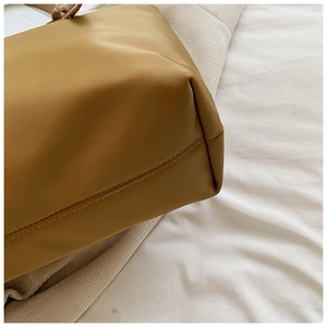 Detailed close-up of precise double stitching on the yellow oxford tote bag base