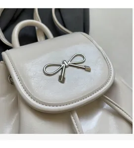 Detail of cream white PU backpack with decorative silver metal bow and fine stitching