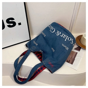 Dettaglio della borsa tote in denim blu con fodera a scacchi rossi e blu all'interno
