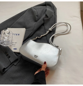 Close-up of metallic silver shoulder bag with wave-shaped opening and knot strap