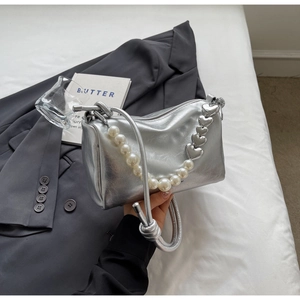 Detail der silbernen Perlenhandtasche mit großen Perlen und Metall-Herz-Kettengurt