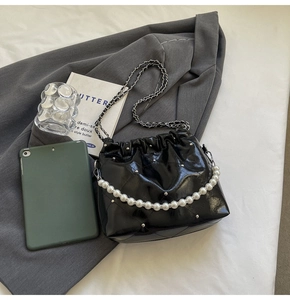 Detail of black quilted leather bucket bag with white pearl handle and silver chain strap
