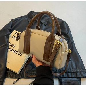 Detail of Boston bag with dual handles, gold hardware, and cream-brown leather patchwork