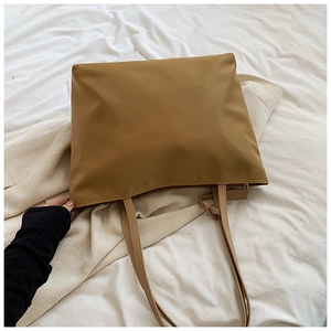 Detail of khaki oxford cloth tote bag on white bedding showing smooth waterproof texture