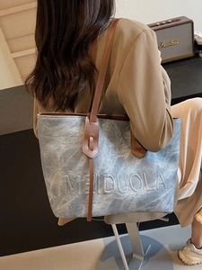 Light blue textured tote bag with brown leather straps shown in a modern interior setting