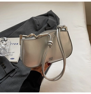 Close-up of metallic silver handbag with a wavy metal frame and knotted strap detail