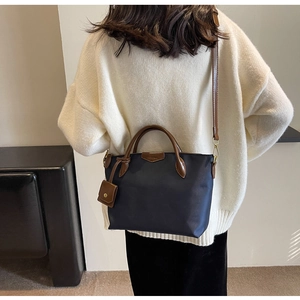 Detail of navy nylon tote bag with brown leather handles and adjustable shoulder strap