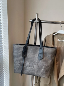 Minimalist grey faux leather tote bag with embossed logo and long shoulder straps
