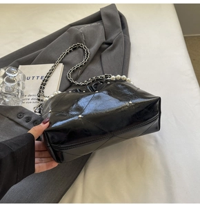 Detail of quilted leather cloud bag with silver studs, chain strap and pearl accents