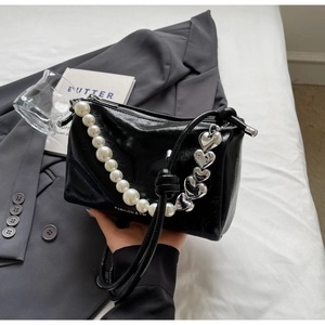 Detailansicht der schwarzen Lederhandtasche mit Perlenkette und Herzanhänger aus Metall