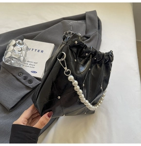 Close-up of quilted black bucket bag with silver studs and elegant pearl handle strap
