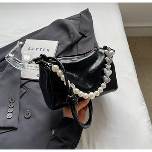 Detail der schwarzen Handtasche aus Glattleder mit Perlenkette und silbernen Herz-Details