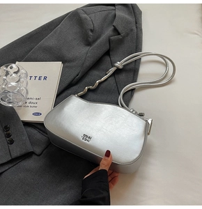 Close-up of metallic silver shoulder bag with unique wave-shaped metal strap connectors