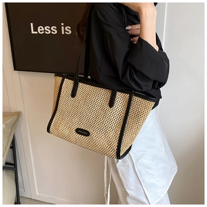 Détail du grand sac cabas en paille avec bordure en cuir noir et fines bandoulières