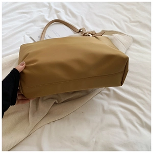 Detail shot of the wide bottom and smooth nylon fabric on this khaki tote bag