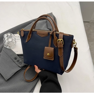 Detail of navy nylon tote bag with brown leather handles and adjustable shoulder strap