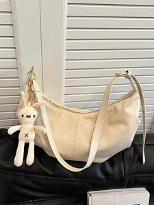 Chic beige dumpling shoulder bag with geometric quilting and cute plush bunny charm