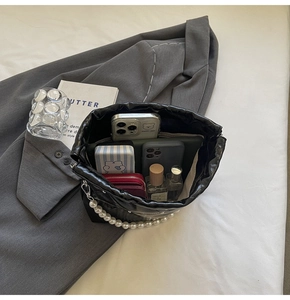 Interior view of black quilted bucket bag showing storage for phones, wallet and perfume