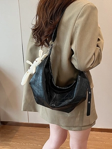 Minimalist black geometric hobo bag with a white plush bunny charm on long strap