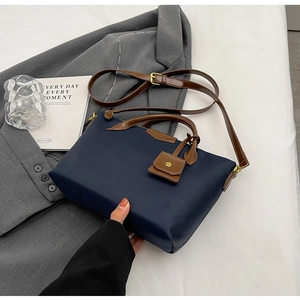 Detail of navy blue nylon tote with brown leather handles and adjustable shoulder strap