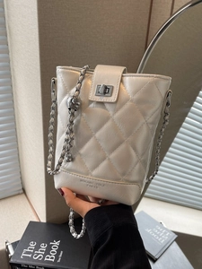 Elegant quilted bucket bag with chain strap and metallic lock shown in soft lighting